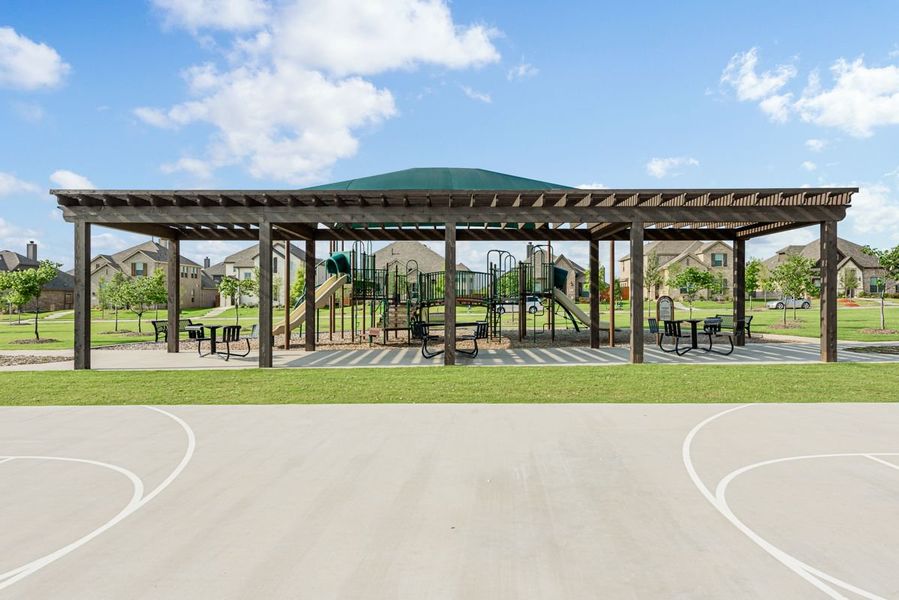 Community park with covered pergola, playground equipment, picnic tables, and basketball court in a residential neighborhood Community park with covered pergola, playground equipment, picnic tables, and basketball court in a residential neighborhood