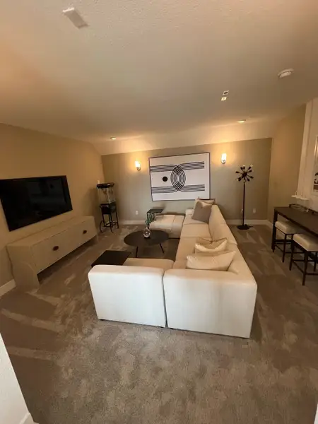 A cozy living area featuring a plush sectional sofa, abstract wall art, and modern lighting accents.