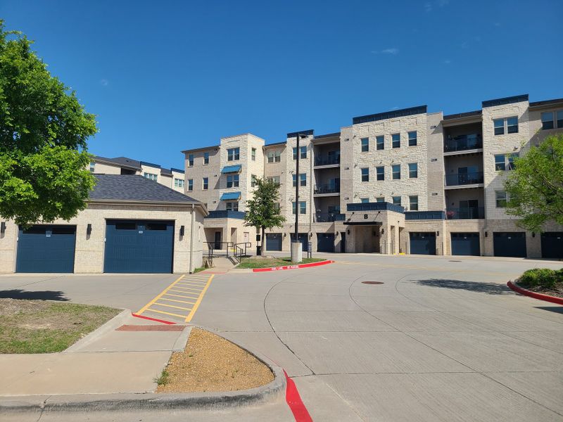 A modern stone apartment complex with garage doors at Gatherings at Twin Creeks by Beazer Homes (Allen, TX). A modern stone apartment complex with garage doors at Gatherings at Twin Creeks by Beazer Homes (Allen, TX).