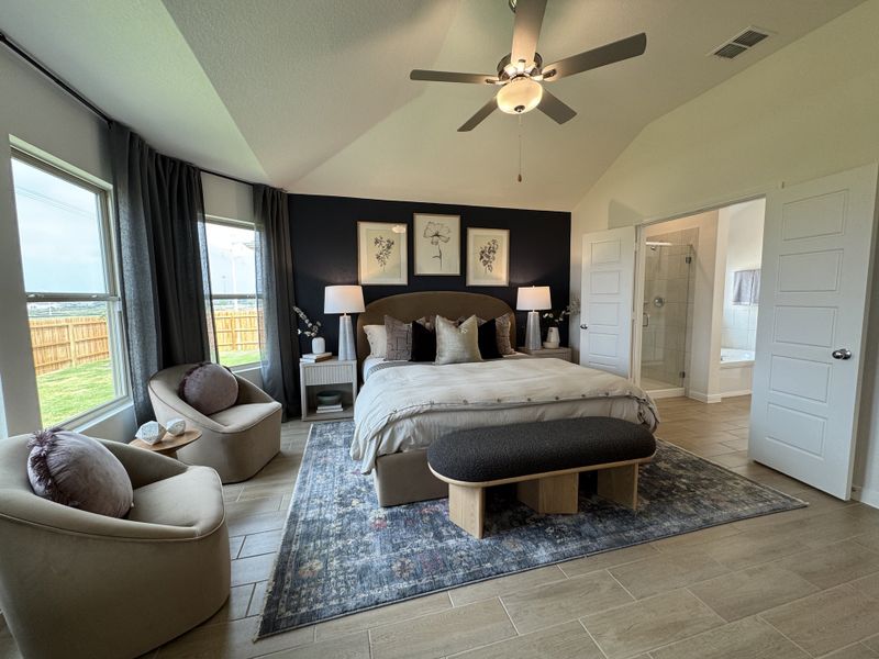 A spacious bedroom with elegant decor, featuring a king-sized bed, cozy seating, and modern ensuite bathroom access.