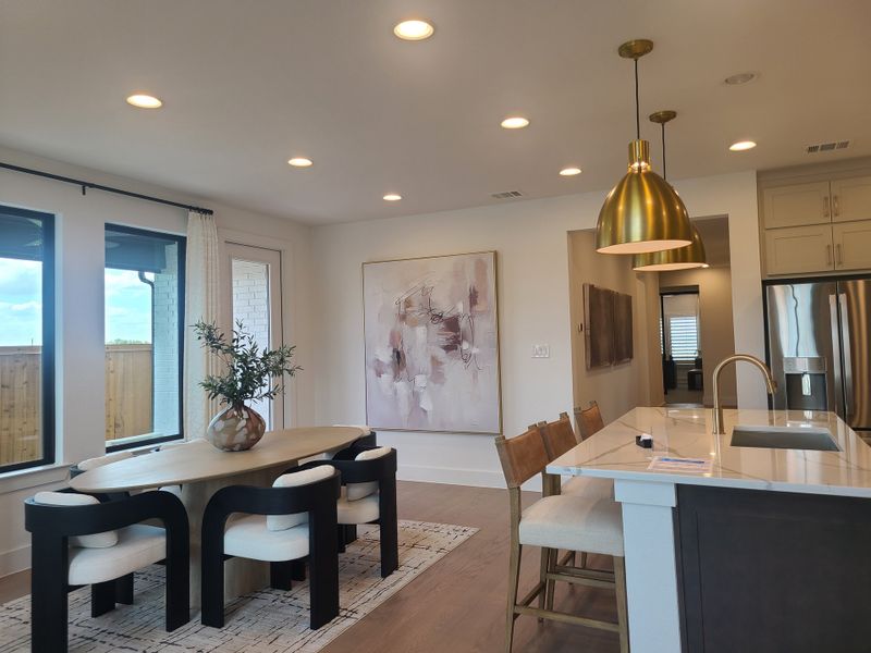A modern dining area with a sleek table, stylish chairs, gold pendant lights, and chic decor.