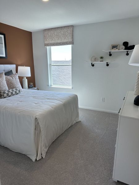 A cozy bedroom featuring a plush bed, decorative shelves, and warm earth tones complements soft carpeting. A cozy bedroom featuring a plush bed, decorative shelves, and warm earth tones complements soft carpeting.