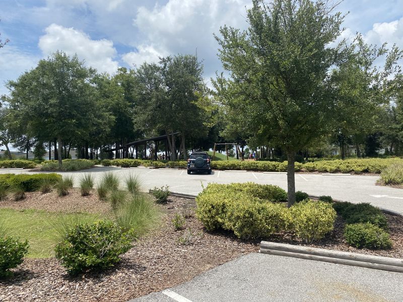 A lush, landscaped community area with trees and parking in Shearwater: Shearwater - Single Family by Lennar (St. Augustine, FL).