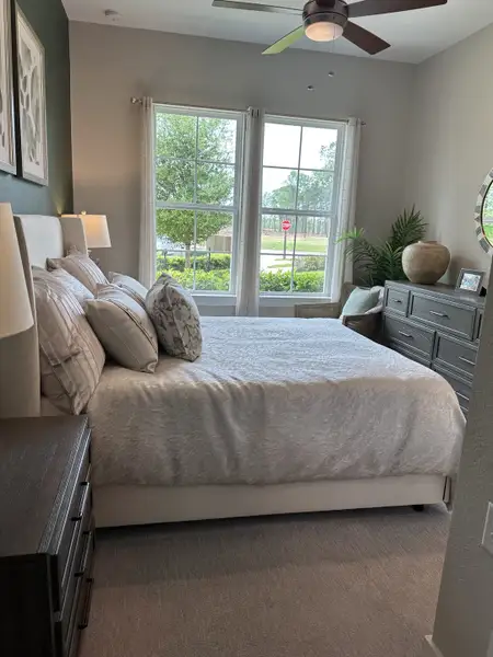 A cozy bedroom with a light-filled window, plush bedding, elegant decor, and modern furniture.