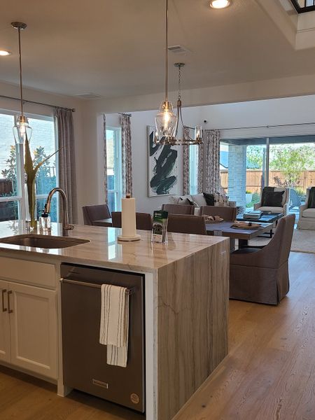 A modern kitchen with a marble island, pendant lighting, and an open layout leading to a cozy living space.