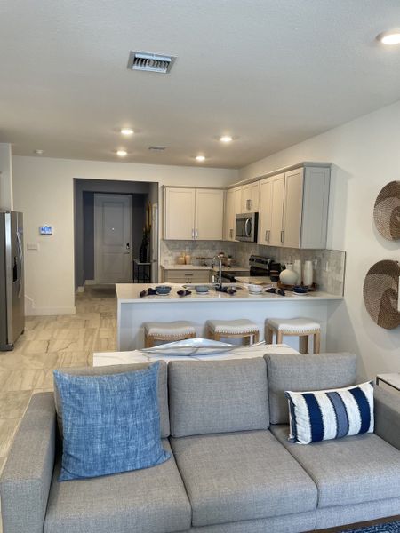 Modern kitchen and living area with neutral tones, cozy seating, and stylish decor.