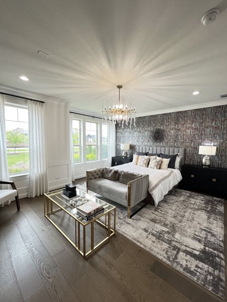 A luxurious bedroom with a chic chandelier, elegant wallpaper, and sophisticated furnishings.