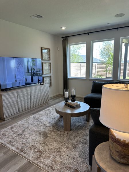 A cozy living room with a sleek TV, textured rug, dark sofa, and modern decor accents. A cozy living room with a sleek TV, textured rug, dark sofa, and modern decor accents.