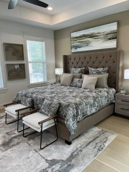 A luxurious bedroom with a tufted headboard, modern art, plush bedding, and elegant lighting.