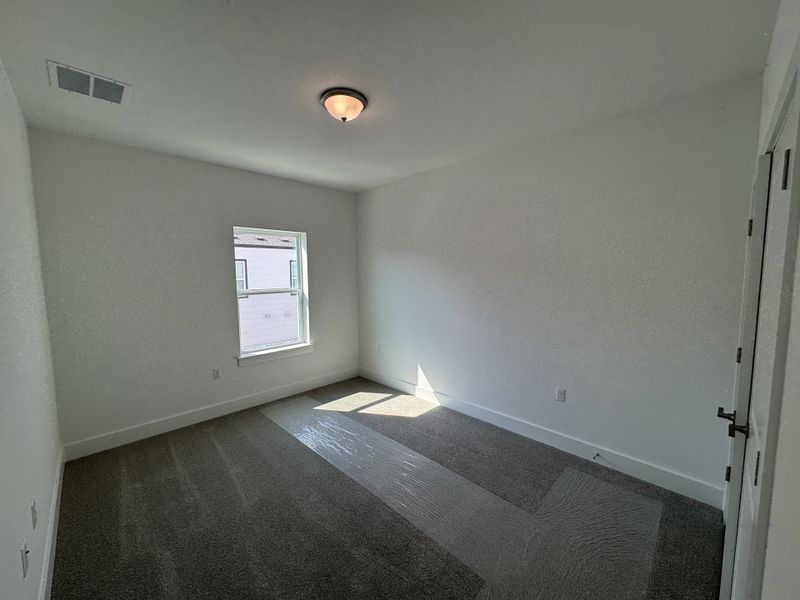 A bright, minimalistic room with neutral carpeting and a single window, offering a blank canvas for personalization. A bright, minimalistic room with neutral carpeting and a single window, offering a blank canvas for personalization.