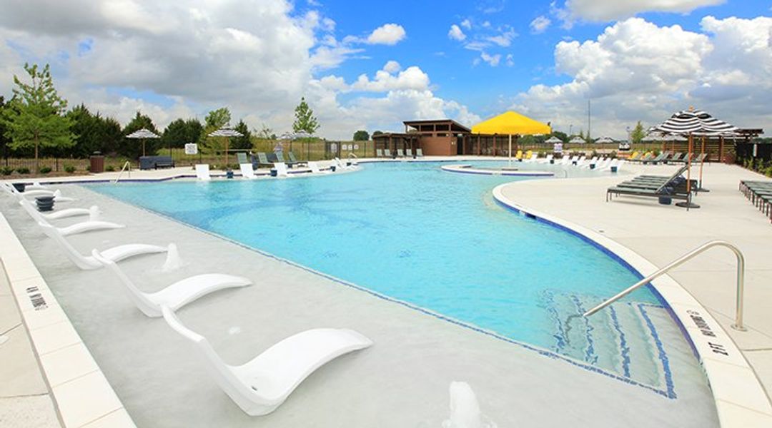 A pool with a lounge chair and umbrellas by it.