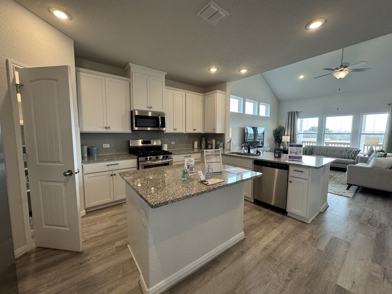 A modern kitchen with granite countertops, stainless steel appliances, and an open-concept living area, flooded with natural light.