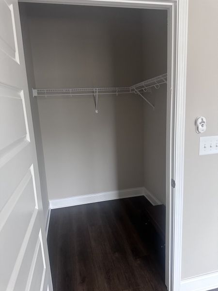 A spacious walk-in closet featuring sleek dark hardwood flooring and wire shelving, perfect for organized storage. A spacious walk-in closet featuring sleek dark hardwood flooring and wire shelving, perfect for organized storage.