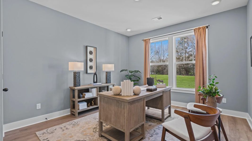 Hardwood flooring secondary bedroom staged as an office space with large windows at Pinebrook by DRB Homes in Woodruff, SC Hardwood flooring secondary bedroom staged as an office space with large windows at Pinebrook by DRB Homes in Woodruff, SC