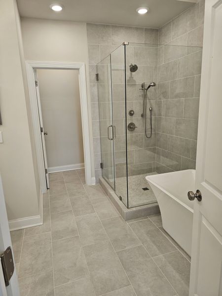 A sleek bathroom featuring a glass-enclosed shower, large bathtub, and elegant grey tiling.