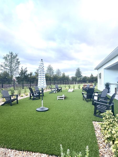 A spacious patio with lawn chairs, corn hole, and a striped umbrella, perfect for relaxing outdoors. A spacious patio with lawn chairs, corn hole, and a striped umbrella, perfect for relaxing outdoors.