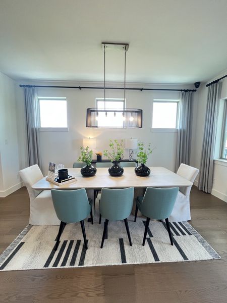 A modern dining room featuring a sleek table, elegant green chairs, and a chic pendant light. A modern dining room featuring a sleek table, elegant green chairs, and a chic pendant light.