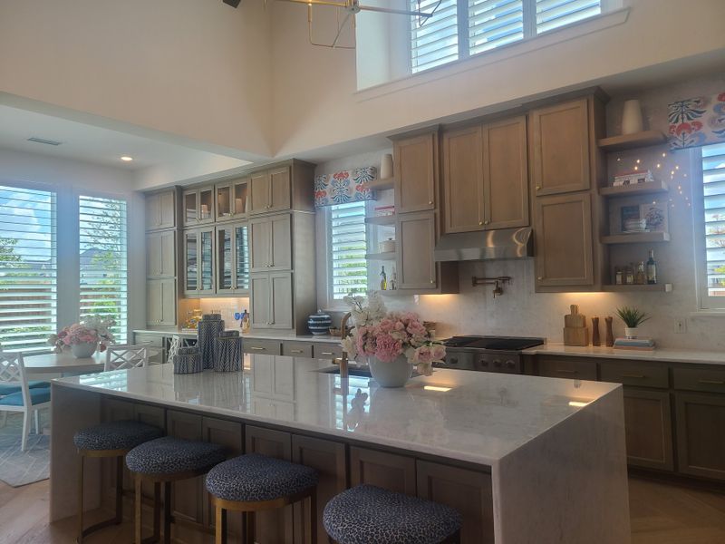 A spacious kitchen with sleek cabinetry, a large marble island, and stylish lighting. Bright and inviting with modern touches.