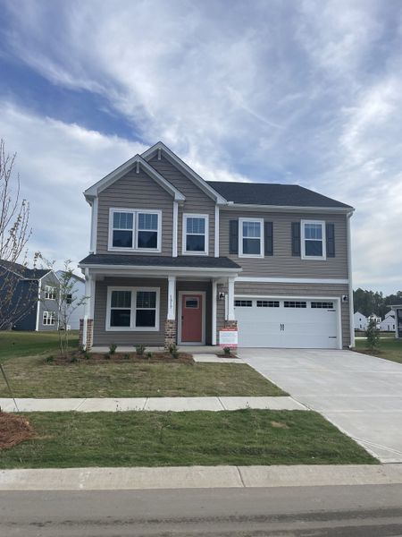 A charming two-story home with a spacious porch and landscaped yard in Homecoming by True Homes (Ravenel, SC).