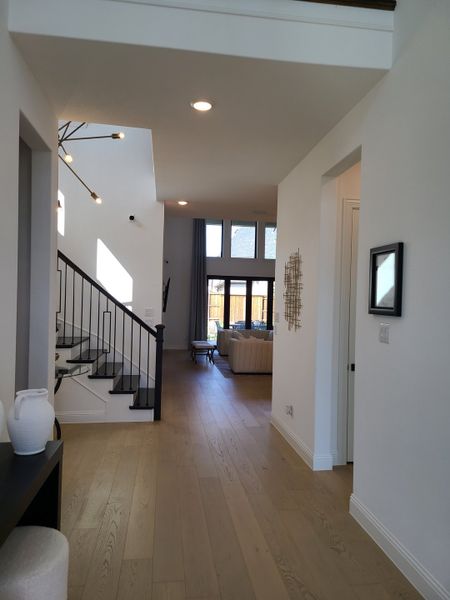 A contemporary hallway featuring elegant wood floors, modern lighting, and an inviting staircase leading to a cozy living area. A contemporary hallway featuring elegant wood floors, modern lighting, and an inviting staircase leading to a cozy living area.