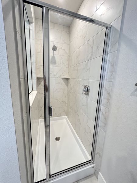 A sleek, modern shower with elegant marble-like tiles and a gleaming glass door. A sleek, modern shower with elegant marble-like tiles and a gleaming glass door.