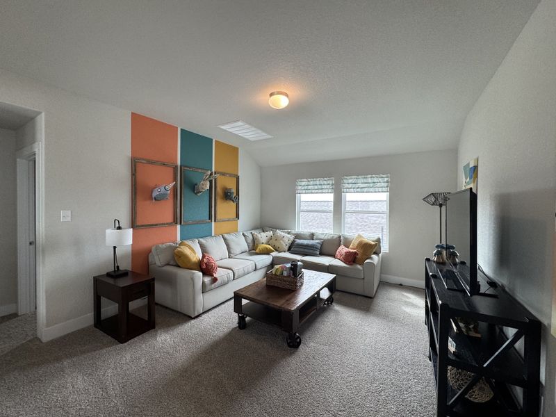 A cozy living room with a large sectional sofa, vibrant accent wall, and natural light from two windows. A cozy living room with a large sectional sofa, vibrant accent wall, and natural light from two windows.