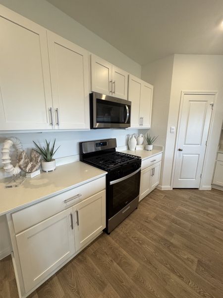 A modern kitchen with sleek white cabinets, stainless steel appliances, and wood flooring. A modern kitchen with sleek white cabinets, stainless steel appliances, and wood flooring.