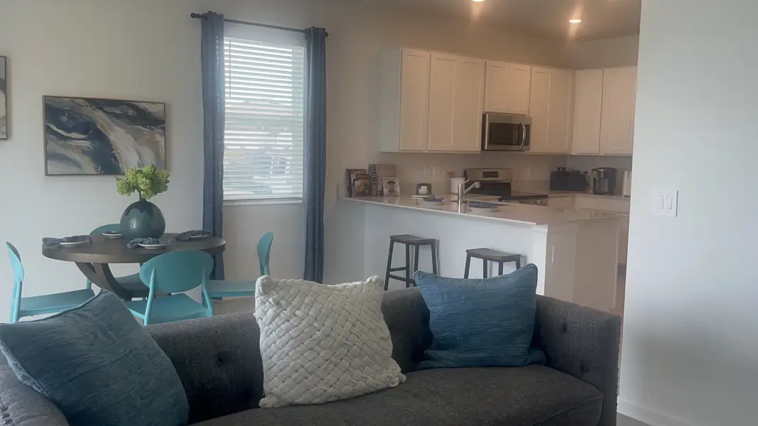 A cozy open-plan kitchen and dining area with modern decor, light cabinetry, and inviting teal accents.