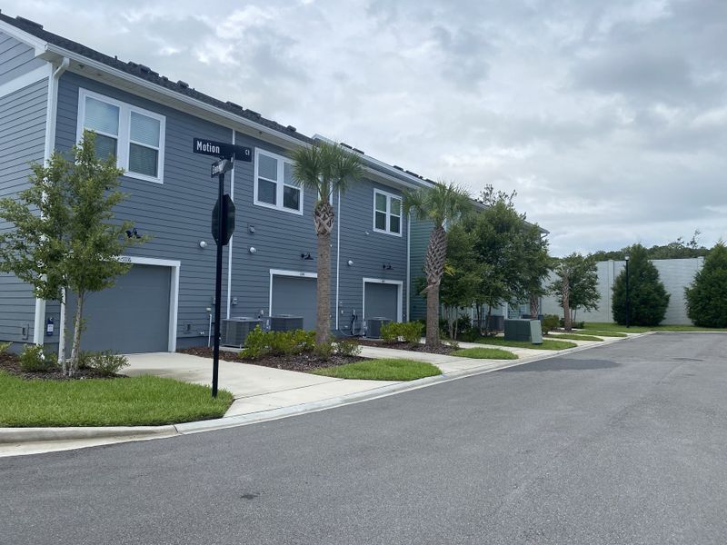 A modern blue-gray townhouse with palm trees in Kettering at eTown - Garden Collection by David Weekley Homes (Jacksonville, FL).