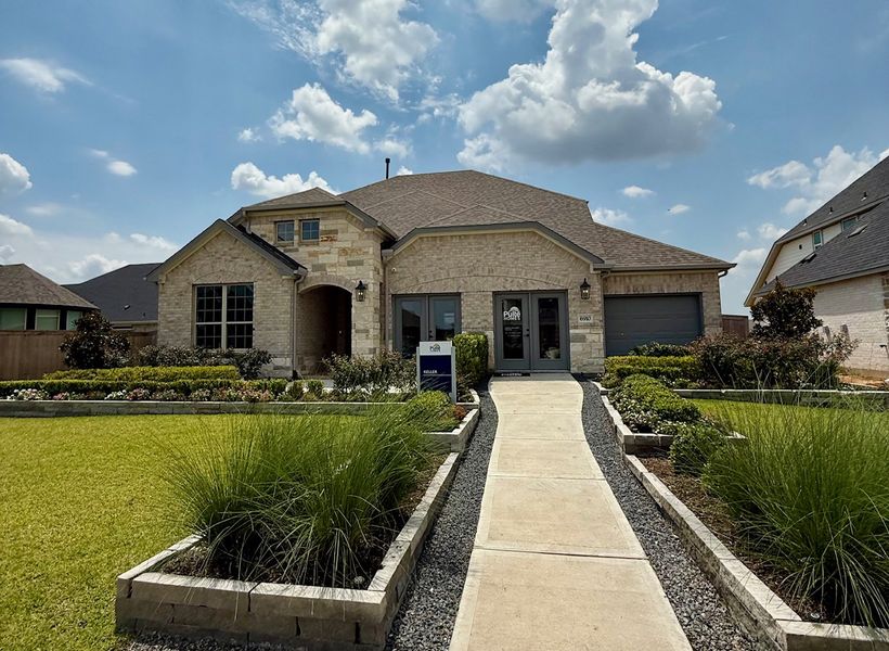A charming light brick home with a well-manicured yard in Arabella on the Prairie by Pulte Homes (Richmond, TX).