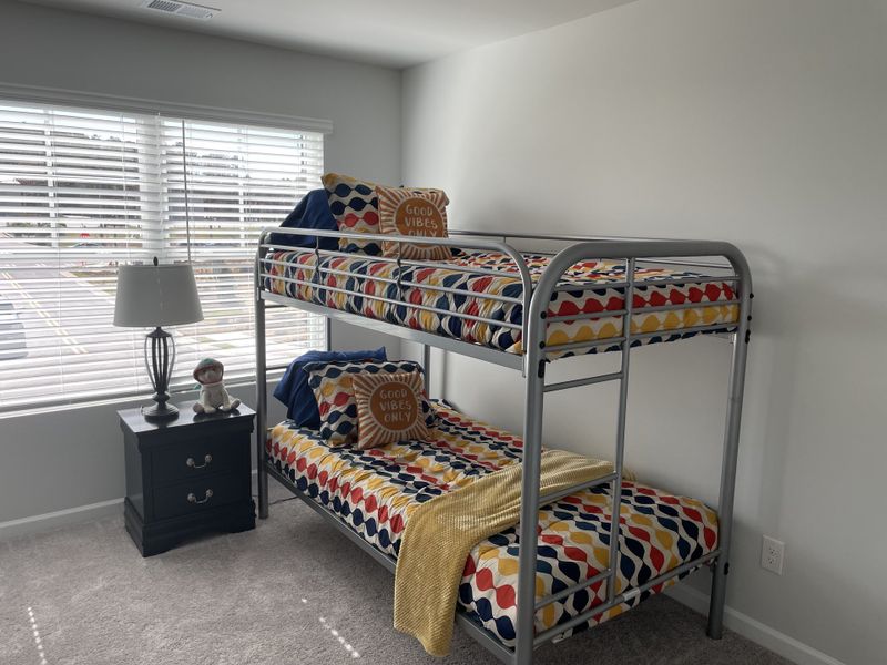 A cozy bedroom with a metal bunk bed, colorful bedding, and a lamp on a nightstand, creating a vibrant space.