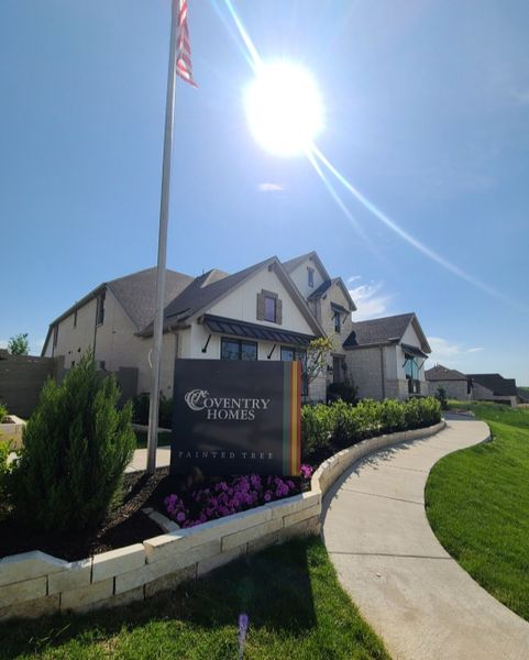 A modern home with lush landscaping and a welcoming path in Painted Tree by Coventry Homes (McKinney, TX).