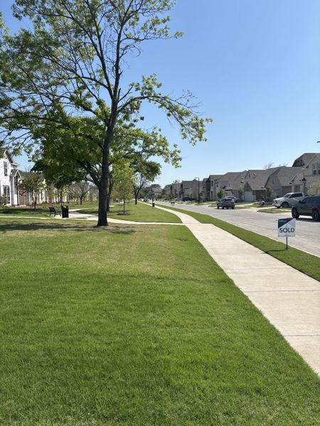 Charming neighborhood with lush greenery in Heritage Park by Brightland Homes (Garland, TX).