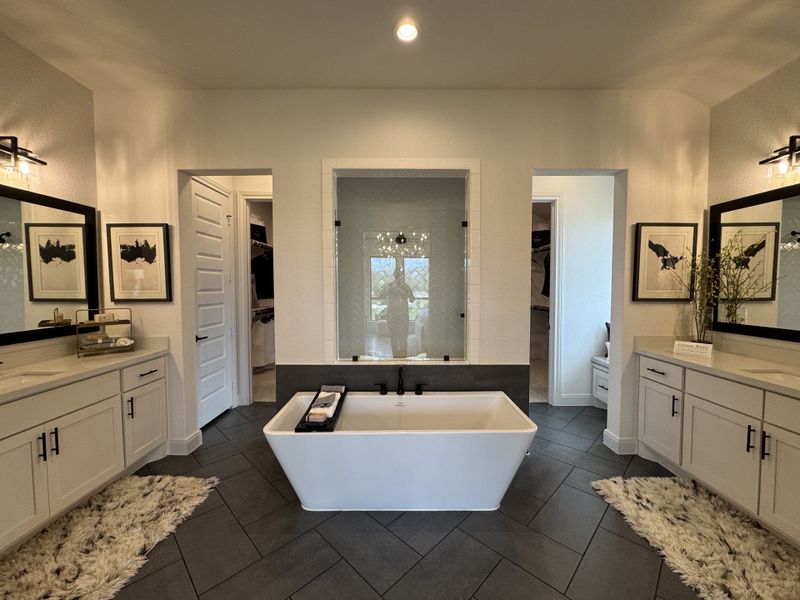 A modern bathroom featuring a central freestanding tub, dual white vanities, and elegant geometric floor tiles. A modern bathroom featuring a central freestanding tub, dual white vanities, and elegant geometric floor tiles.