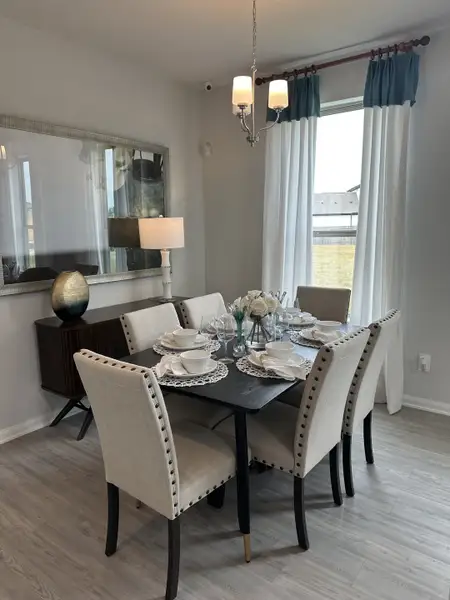 A cozy dining area featuring a sleek black table, upholstered chairs, and chic lighting with elegant decor accents.
