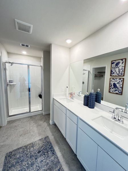 A sleek bathroom with a glass shower, dual sinks, and elegant decor.