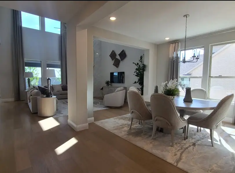 An elegant open-concept living and dining area with high ceilings, plush seating, and large windows that bring in natural light.