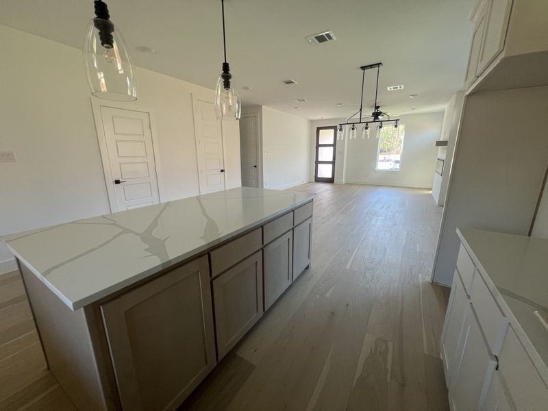 A modern kitchen with sleek countertops, pendant lighting, and light wood flooring, perfect for a stylish home.