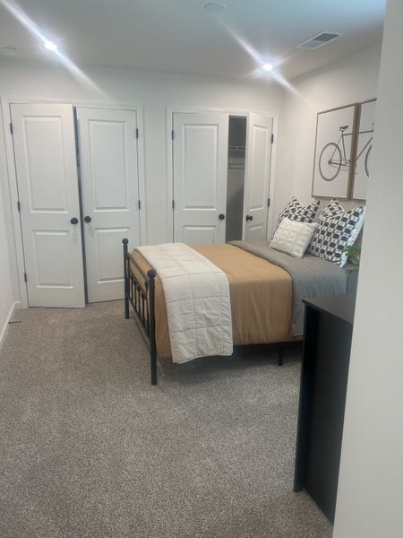 A cozy bedroom with a metal bed frame, soft bedding, and dual closet doors, accented by bicycle-themed wall art. A cozy bedroom with a metal bed frame, soft bedding, and dual closet doors, accented by bicycle-themed wall art.