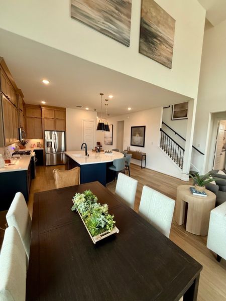 An open-concept dining and kitchen area with modern decor, featuring wooden cabinetry and a spacious layout. An open-concept dining and kitchen area with modern decor, featuring wooden cabinetry and a spacious layout.