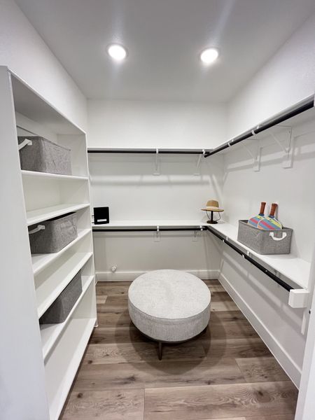 A spacious walk-in closet with sleek shelving, modern lighting, and elegant wood flooring. A spacious walk-in closet with sleek shelving, modern lighting, and elegant wood flooring.