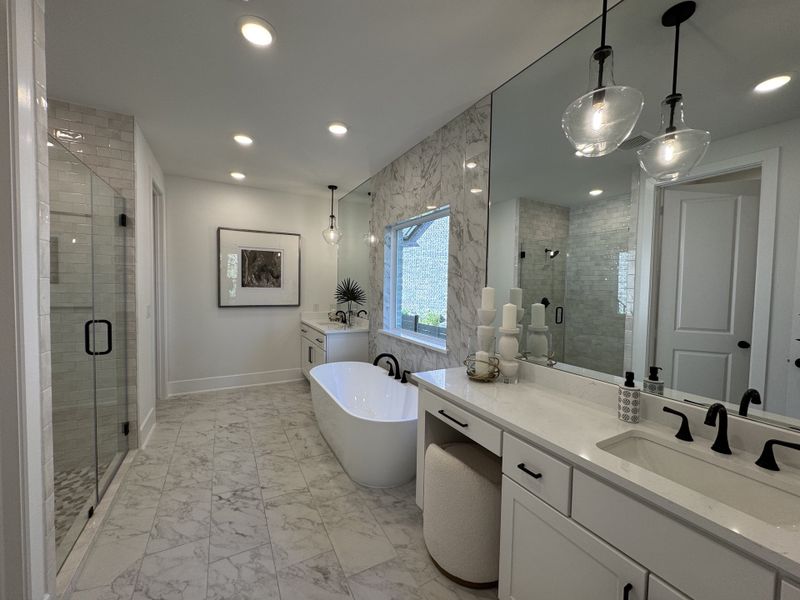 Elegant bathroom with marble tiles, freestanding tub, sleek vanity, and modern glass shower.