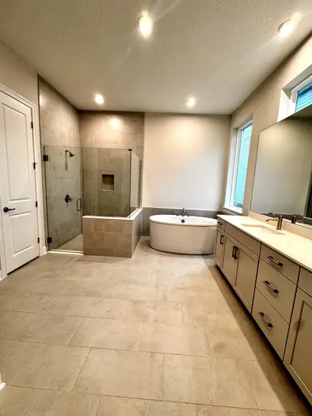 A modern bathroom with a frameless glass shower, freestanding tub, and dual-sink vanity in neutral tones. A modern bathroom with a frameless glass shower, freestanding tub, and dual-sink vanity in neutral tones.