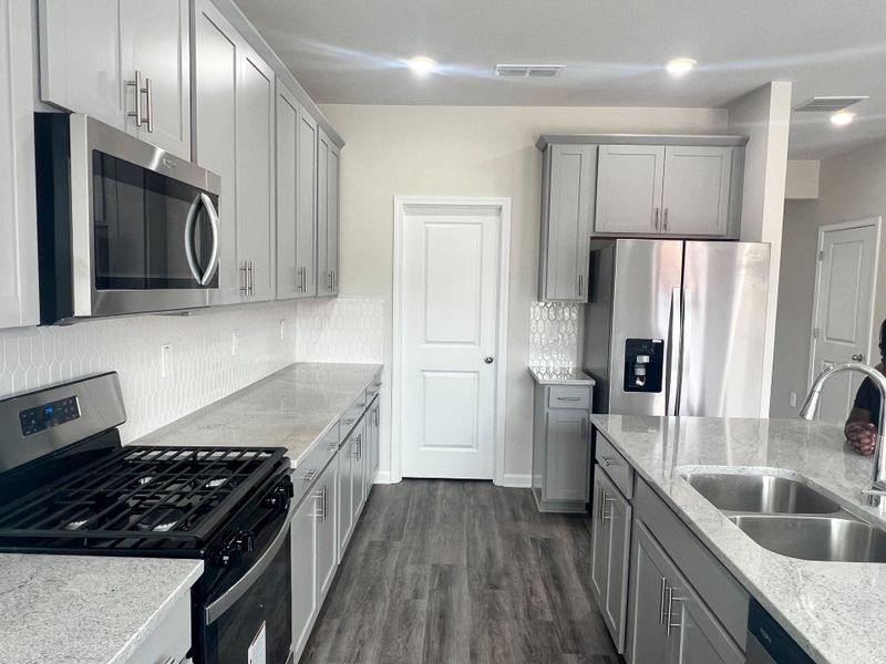 A modern kitchen with sleek gray cabinets, stainless steel appliances, and elegant countertops. A modern kitchen with sleek gray cabinets, stainless steel appliances, and elegant countertops.