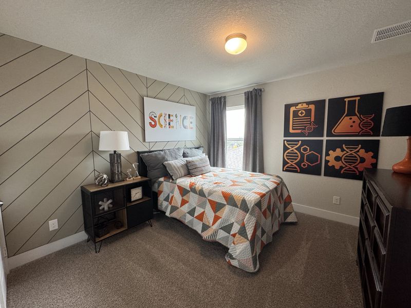A cozy bedroom featuring a patterned accent wall and vibrant decor with scientific themes. A cozy bedroom featuring a patterned accent wall and vibrant decor with scientific themes.