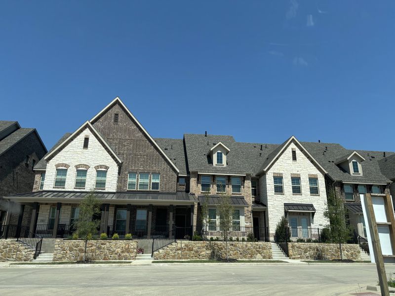 Elegant row of brick and stone homes with lush landscaping in Bayside by Beazer Homes (Rowlett, TX).