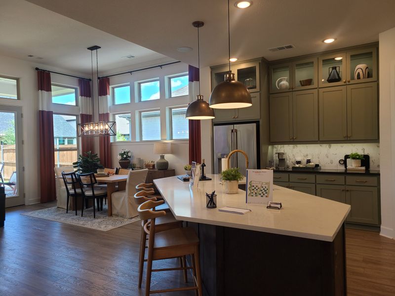 A modern kitchen and dining area with sleek cabinetry, pendant lighting, and large windows offering abundant natural light. A modern kitchen and dining area with sleek cabinetry, pendant lighting, and large windows offering abundant natural light.