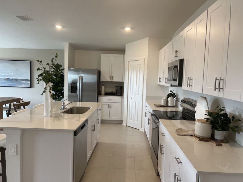 A modern kitchen featuring white cabinetry, sleek countertops, and stainless steel appliances, with elegant decor accents.