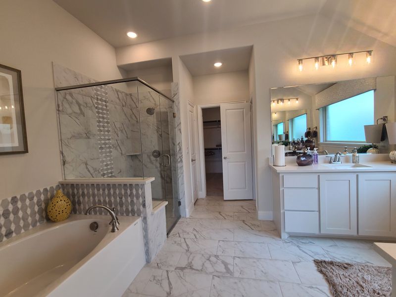 Elegant bathroom with marble tiles, glass shower, white vanity, and modern lighting.