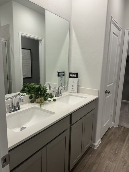 A modern bathroom with dual sinks, sleek cabinetry, and a large mirror, accented by a touch of greenery. A modern bathroom with dual sinks, sleek cabinetry, and a large mirror, accented by a touch of greenery.
